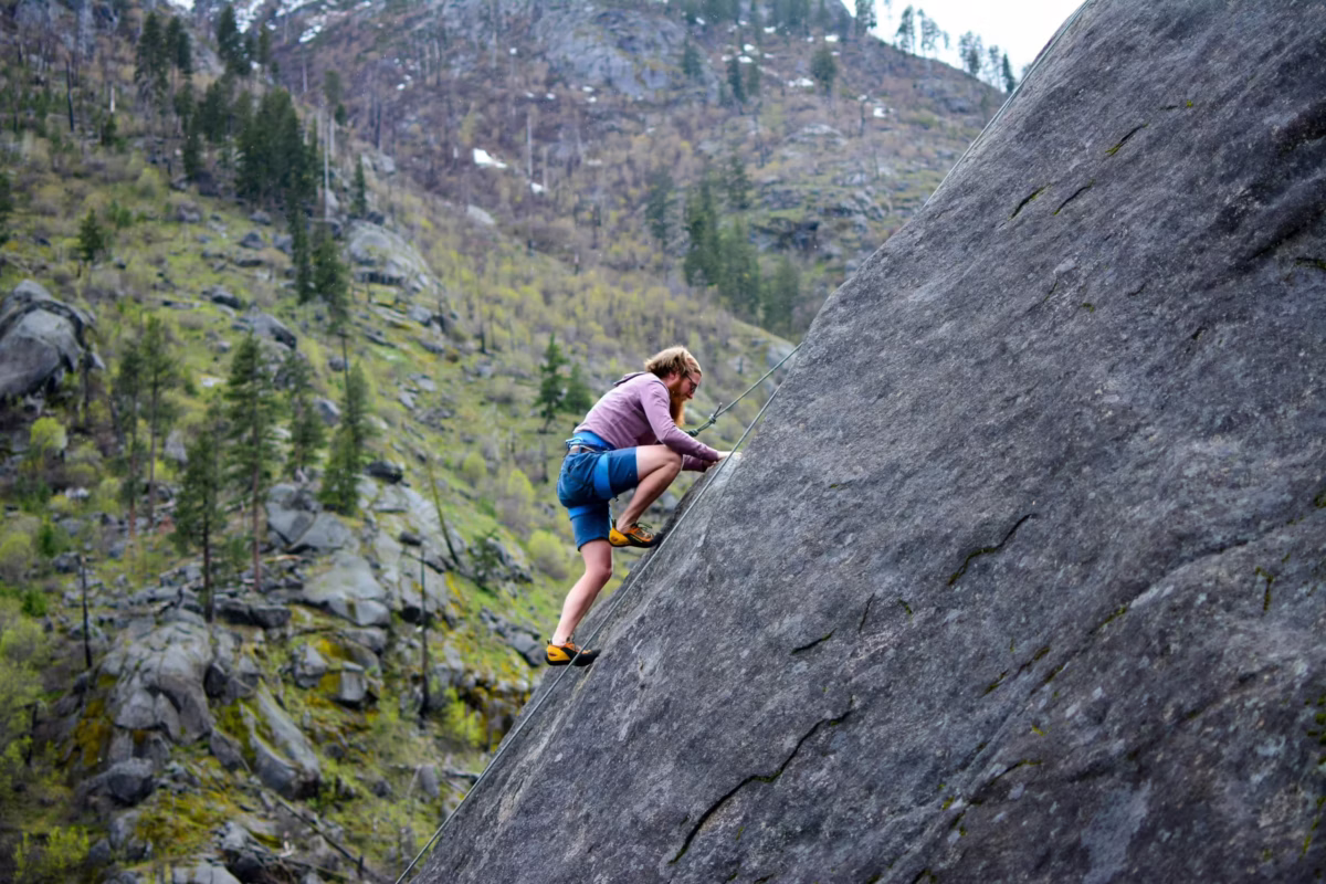 Person climbing a rock representing overcoming obstacles to self-improvement.