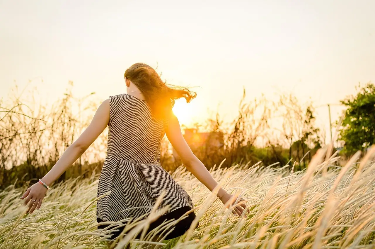 Woman in a field in sunset, reflecting on ger spiritual awakening journey.