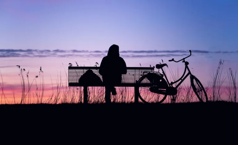 Person sitting in sunset, discovered ways to reduce stress and anxiety during difficult times.