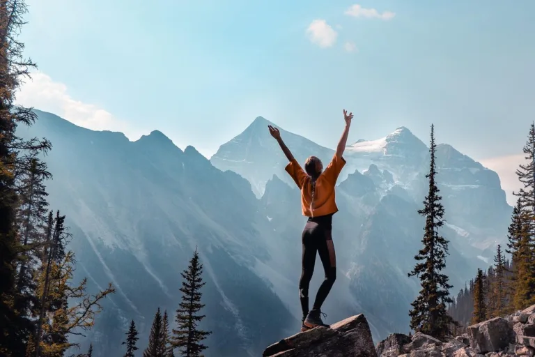 Woman on top of a mountain, symbolizing achieving your goals.