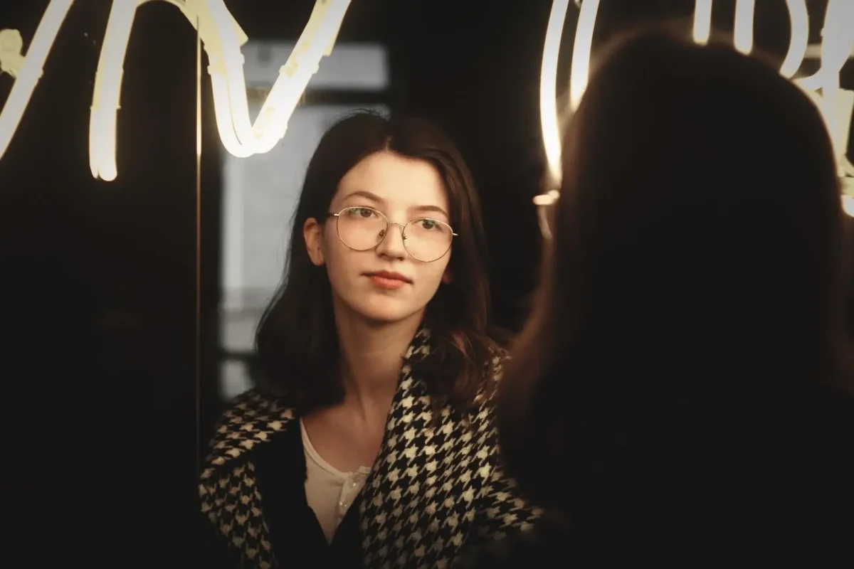 Woman speaking positive affirmations to herself in the mirror.