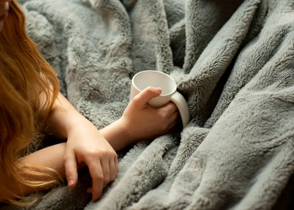 Woman wrapped in a weighted blanket, one of self-care items.