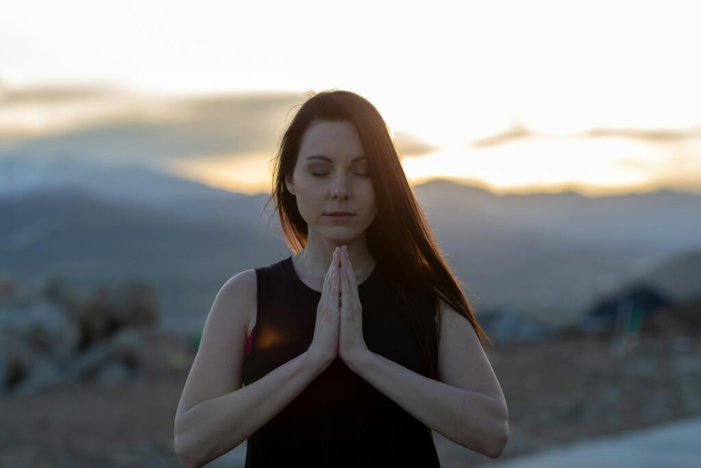 Woman on a mountain practicing positive affirmations.