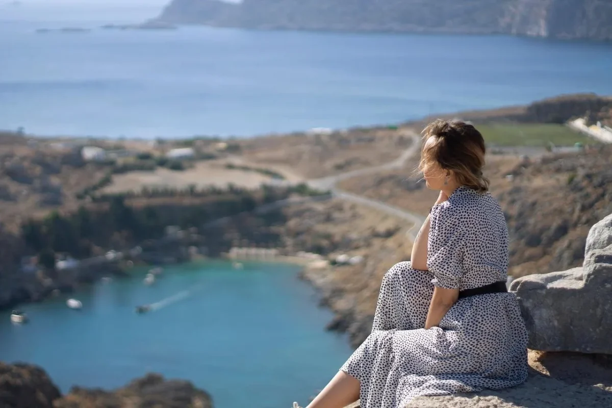 Woman looking down on a mountain, representing the potential of building good habits.