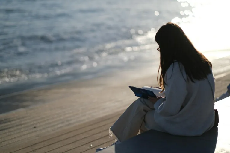Woman by the ocean reflecting on journal prompts for healing.