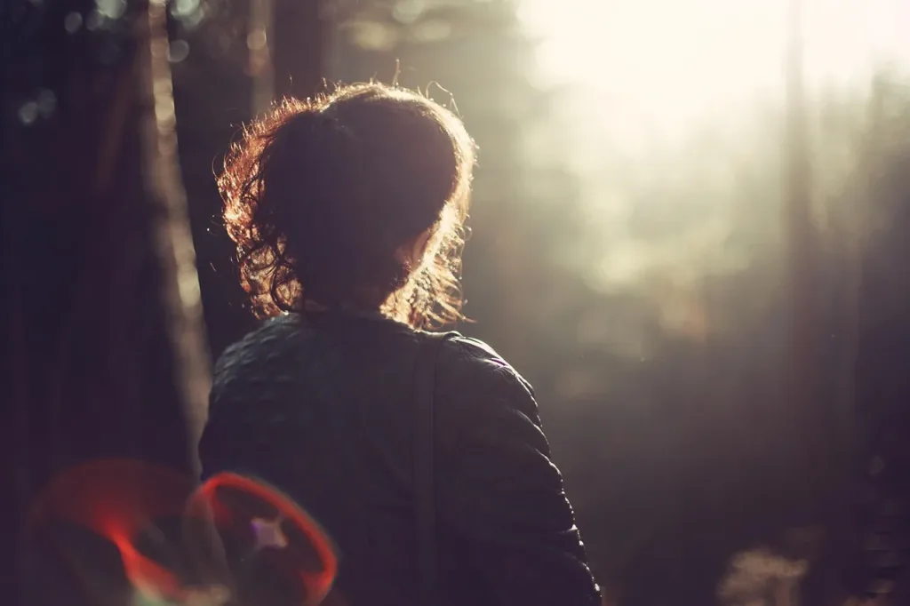 Woman looking at sunlight, representing the positive effect of positive affirmations for stress and anxiety.