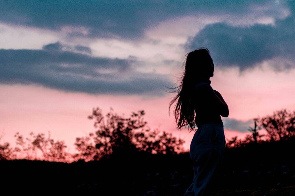 Woman in nature in the sunset, thinking about mindset shifts that explain how to feel good about yourself.