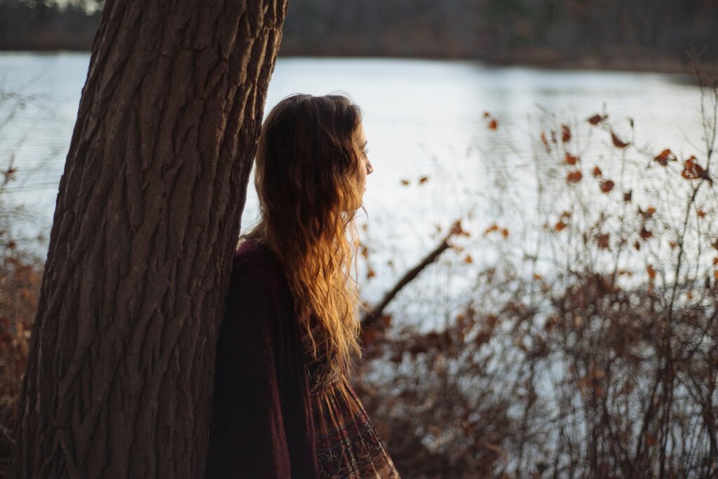 Woman by the water, thinking and reflecting on the journey of reinventing yourself.