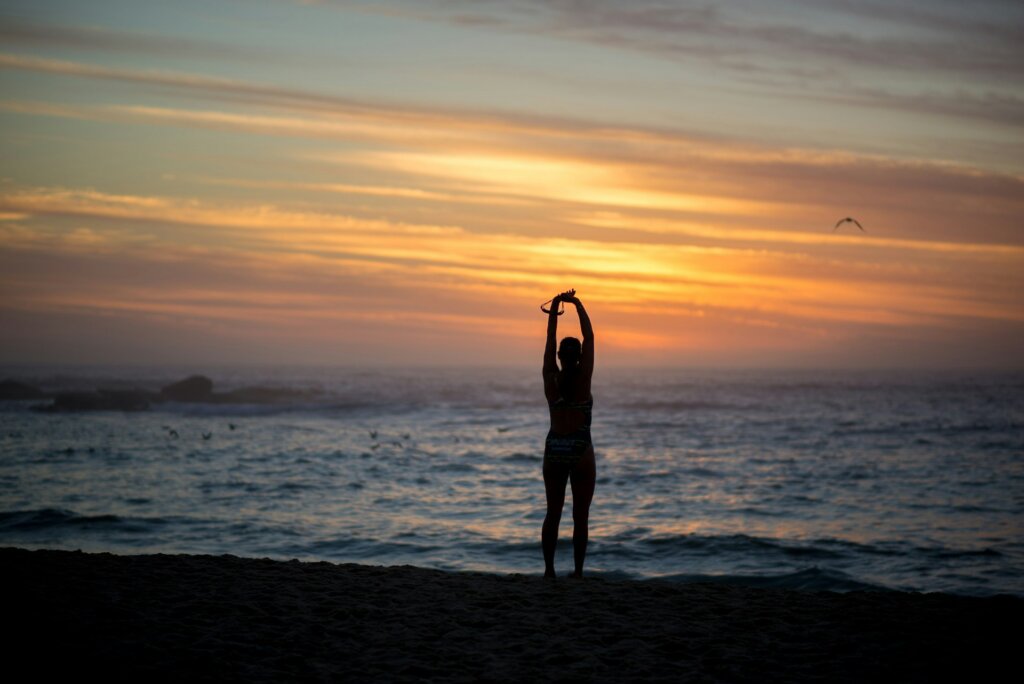 woman on the beach, stretching, doing yoga as a way to show self-respect.
