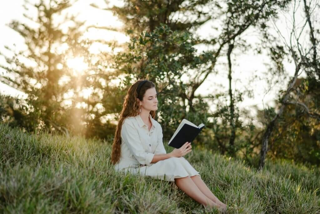 Woman sitting in nature, learning how to start a manifestation journal.