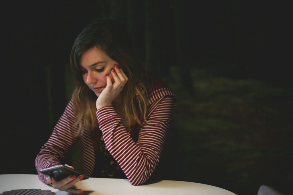 Woman looking at her phone, representing comparison that should be released in order to learn how to start loving yourself.