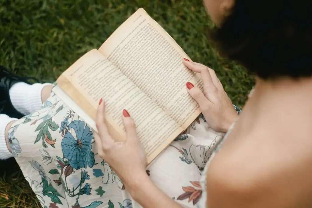Woman in a park, reading the best self-help books of all time.