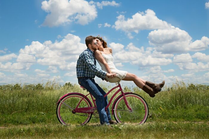 Happy couple riding a bike together after learning how to manifest love and attract your soulmate.