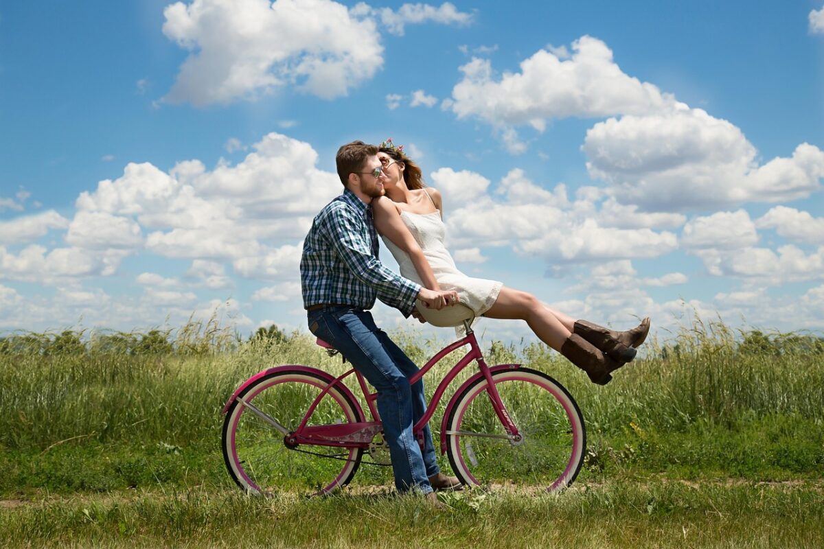 Happy couple riding a bike together after learning how to manifest love and attract your soulmate.