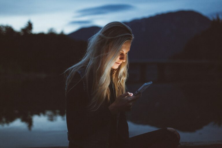 Woman scrolling on her phone, wanting to learn how to do a digital detox.