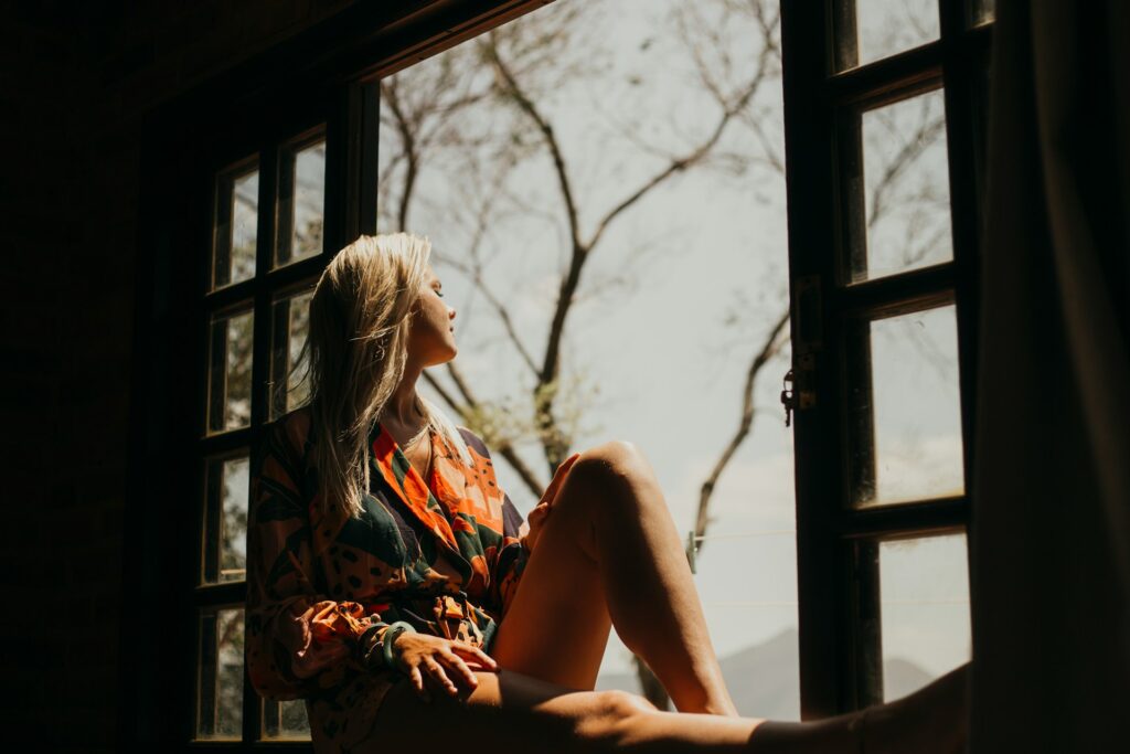 Woman looking out the window, takign a break from social media and scrolling.
