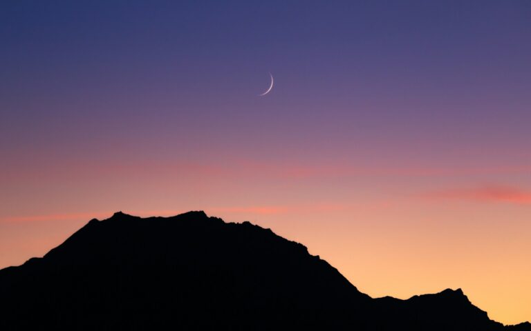 A new moon showing in the sky, representing a beginning of a new moon manifestation ritual.